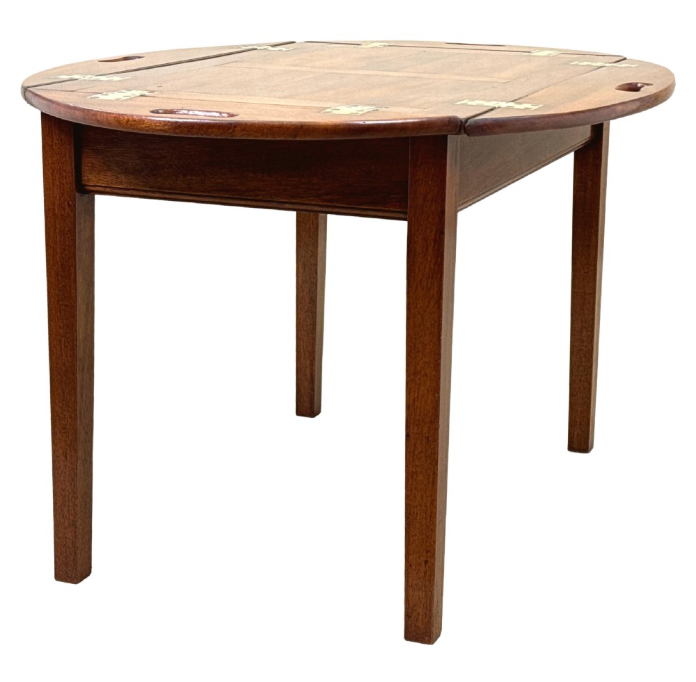 A Georgian mahogany oval butler tray table featuring brass-hinged drop sides with cut-out hand-grips resting on four square legs. View VI