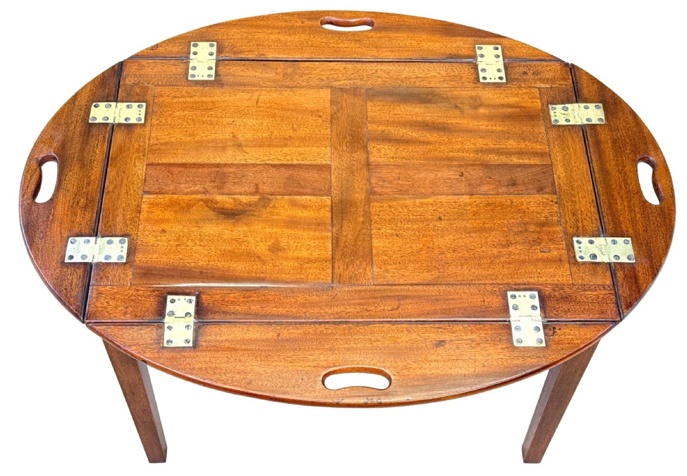 A Georgian mahogany oval butler tray table featuring brass-hinged drop sides with cut-out hand-grips resting on four square legs. View VIII