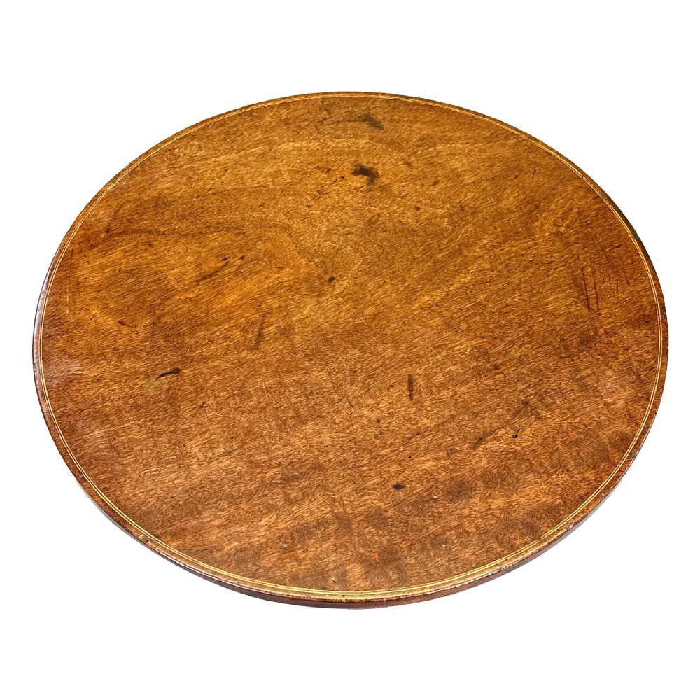 An antique Georgian circular mahogany wine table displayed with its top tilted upwards, supported by a turned pedestal column and a tripod base with three curved legs. View VIII