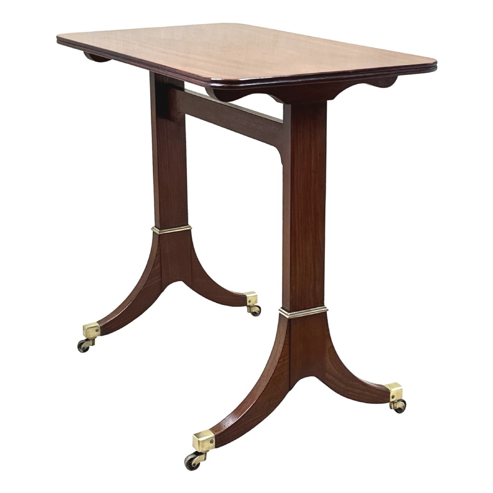 A small Georgian dark mahogany library table featuring a rectangular top, a stretchered trestle base, down-swept sabre legs, and brass castors. View II