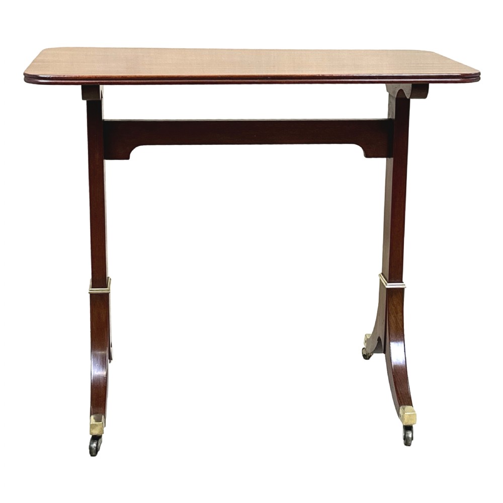 A small Georgian dark mahogany library table featuring a rectangular top, a stretchered trestle base, down-swept sabre legs, and brass castors. View III