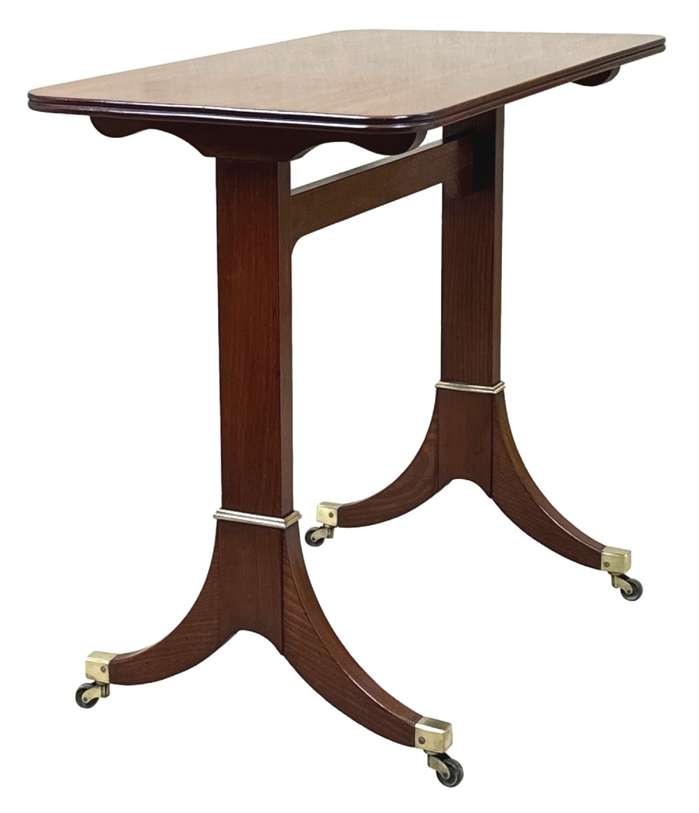 A small Georgian dark mahogany library table featuring a rectangular top, a stretchered trestle base, down-swept sabre legs, and brass castors. View V