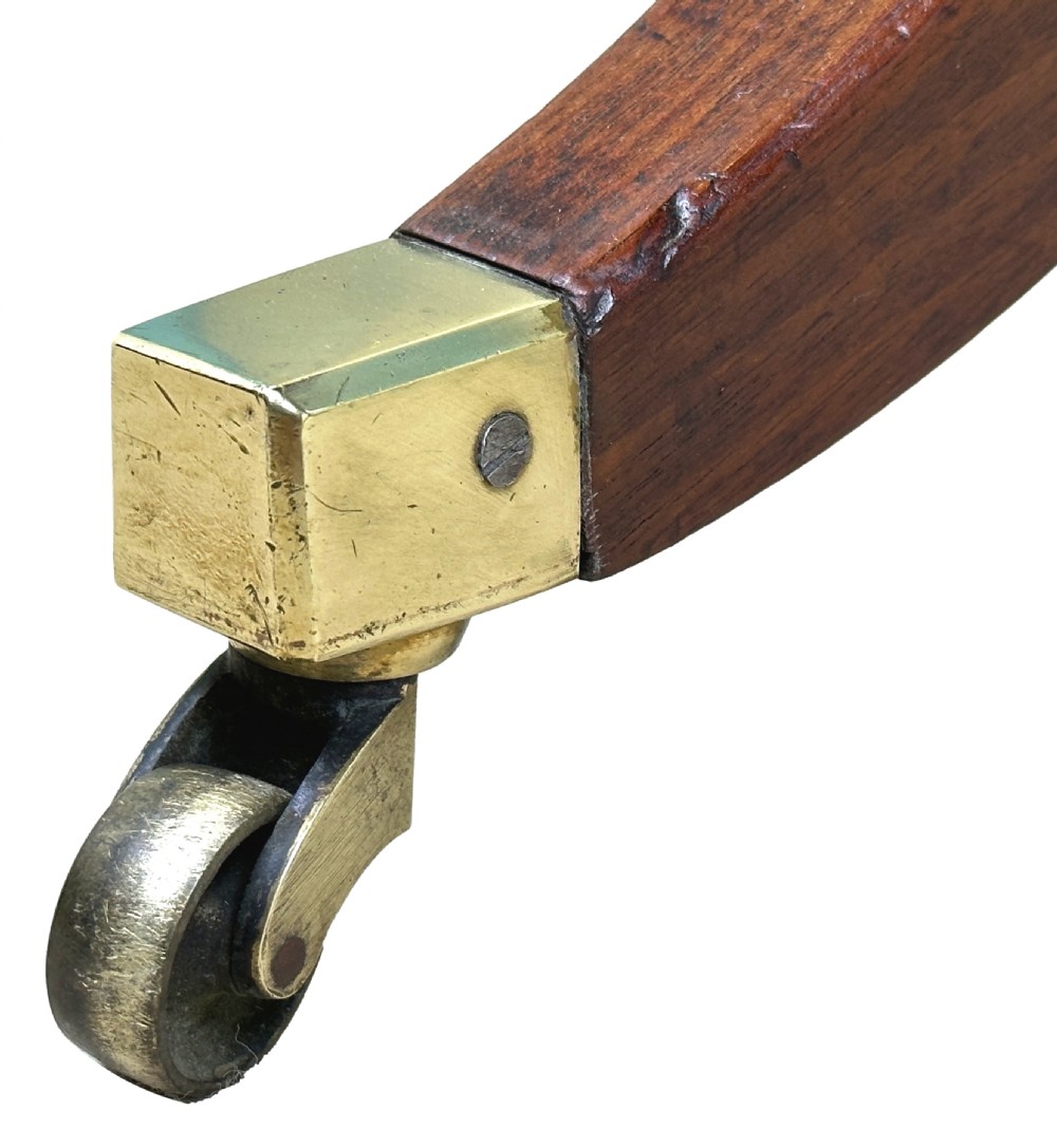 A small Georgian dark mahogany library table featuring a rectangular top, a stretchered trestle base, down-swept sabre legs, and brass castors. View VI
