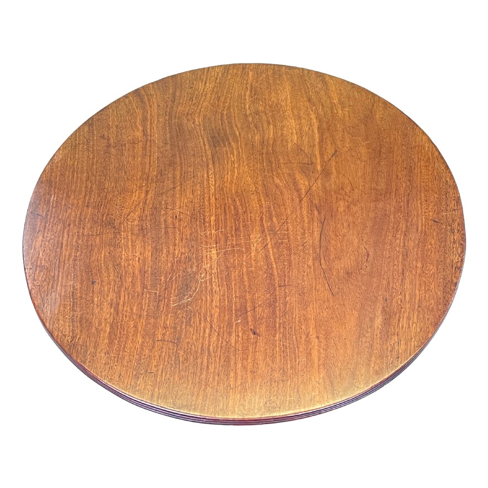 A circular Georgian mahogany wine table with a turned central column resting on a tripod base with reeded legs. View VI