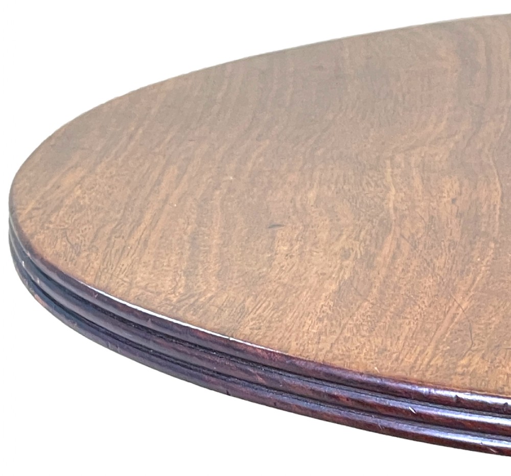A circular Georgian mahogany wine table with a turned central column resting on a tripod base with reeded legs. View VII
