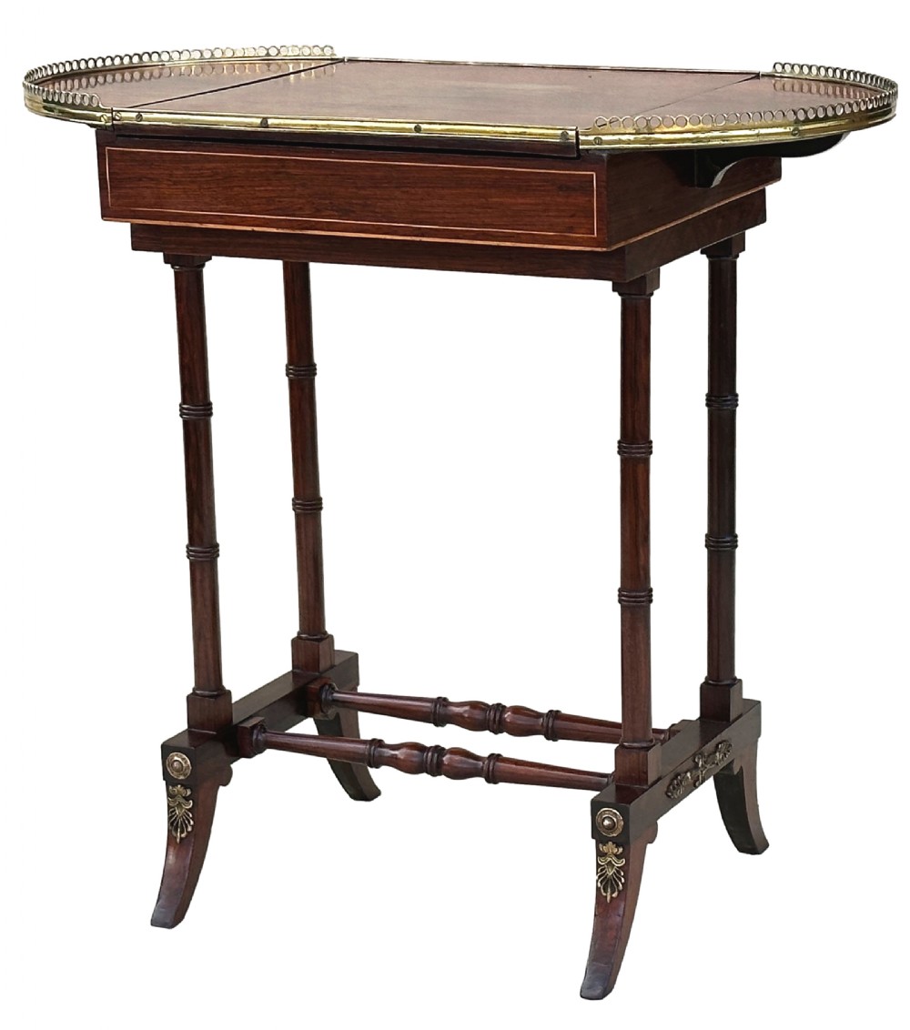 A dark rosewood Regency games table featuring slender ring-turned legs, a pierced brass gallery railing on top, and brass mounts on splayed feet.