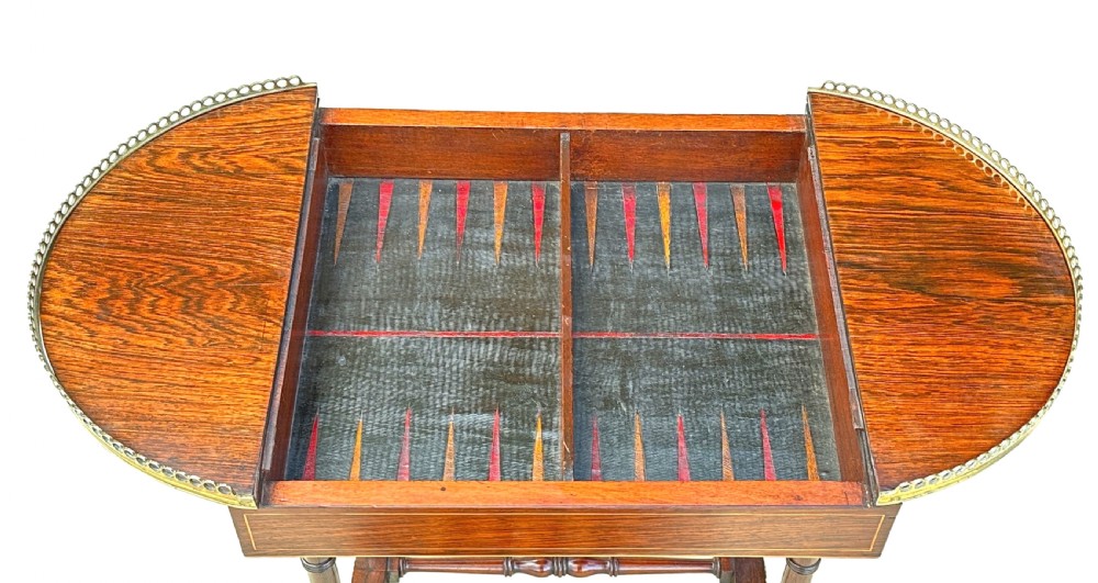 A dark rosewood Regency games table featuring slender ring-turned legs, a pierced brass gallery railing on top, and brass mounts on splayed feet. View IV