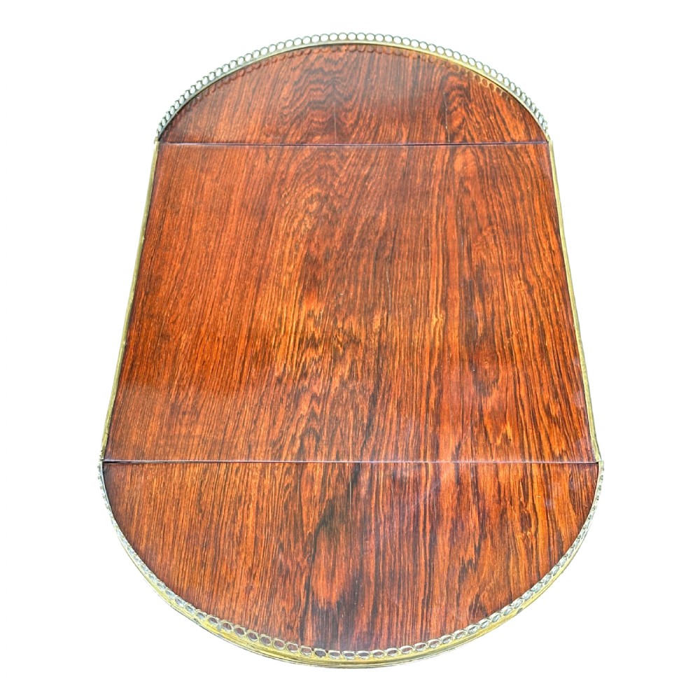 A dark rosewood Regency games table featuring slender ring-turned legs, a pierced brass gallery railing on top, and brass mounts on splayed feet. View V