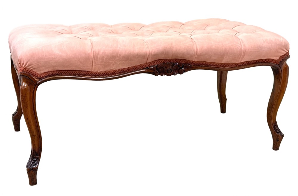 A rectangular Victorian walnut salon stool featuring a button-tufted pink fabric top, carved serpentine apron, and four cabriole legs. View VI
