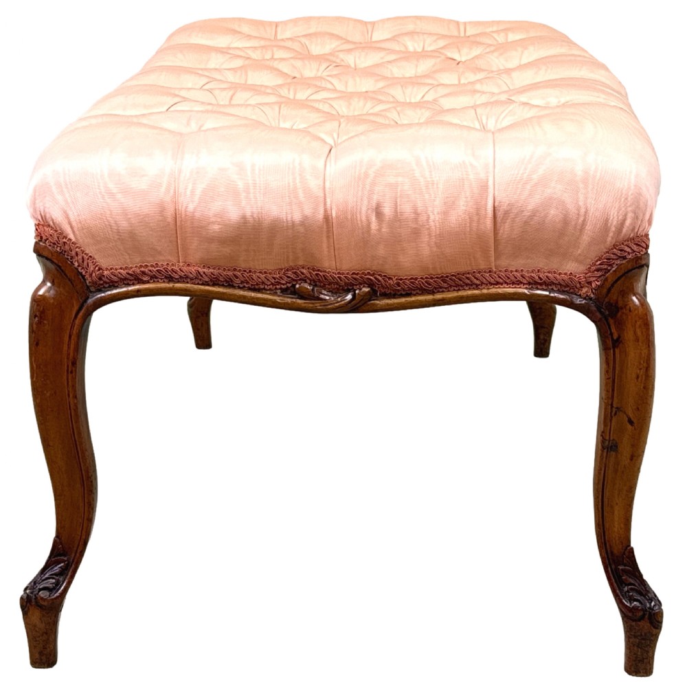 A rectangular Victorian walnut salon stool featuring a button-tufted pink fabric top, carved serpentine apron, and four cabriole legs. View VIII