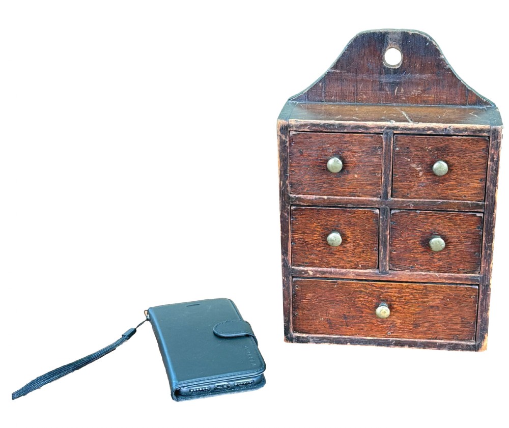 A 19th-century dark oak and pine wall-hanging spice box featuring five small drawers with brass knobs and a shaped top backboard with a hanging hole. View III