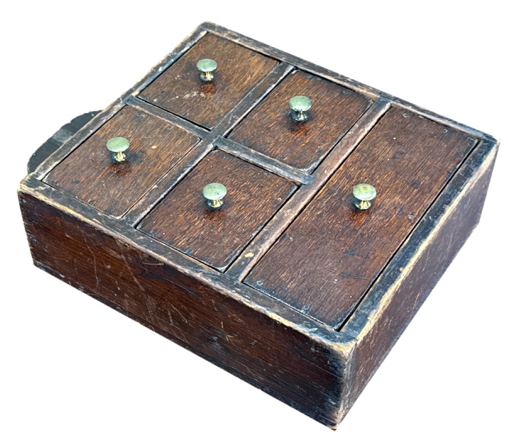 A 19th-century dark oak and pine wall-hanging spice box featuring five small drawers with brass knobs and a shaped top backboard with a hanging hole. View VII