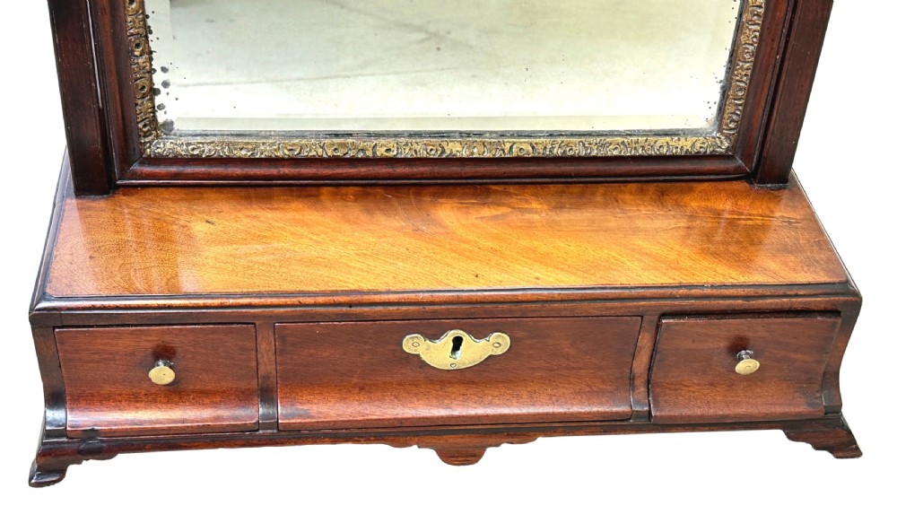 An 18th-century Georgian mahogany toilet mirror featuring a rectangular swivelling glass with a gilded inner border set above a drawer base with brass handles. View VIII