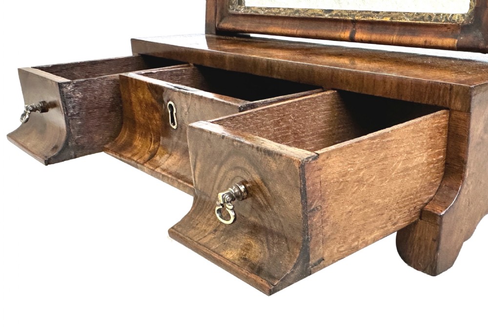 A Georgian walnut dressing table mirror with an adjustable rectangular glass, gilded inner border, and a base containing three concave drawers with brass handles. View III