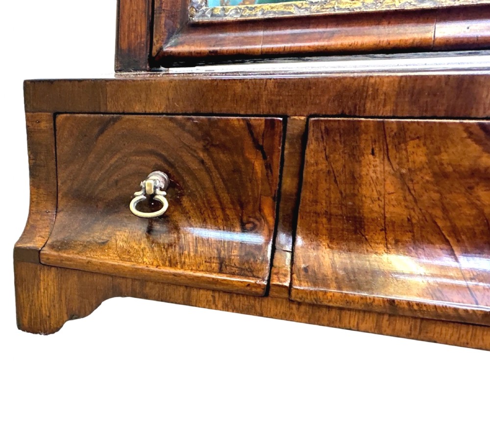 A Georgian walnut dressing table mirror with an adjustable rectangular glass, gilded inner border, and a base containing three concave drawers with brass handles. View VI