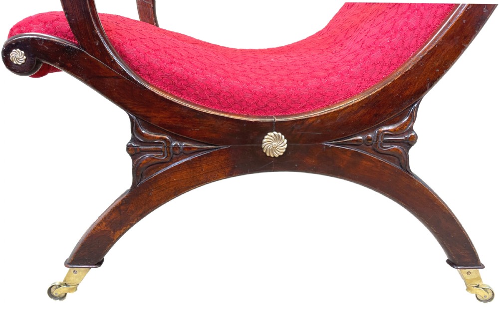 A Regency mahogany library armchair featuring button-backed red upholstery, curved scroll arms, and brass castors. View II