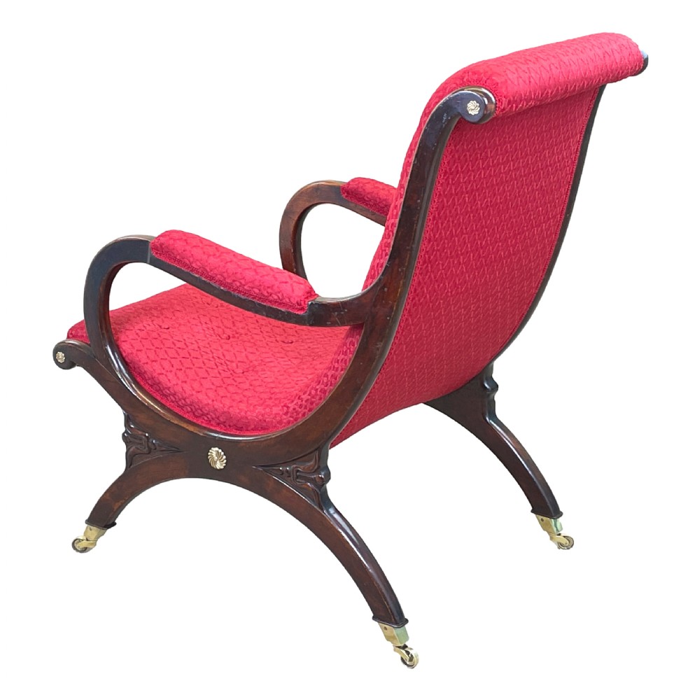 A Regency mahogany library armchair featuring button-backed red upholstery, curved scroll arms, and brass castors. View III