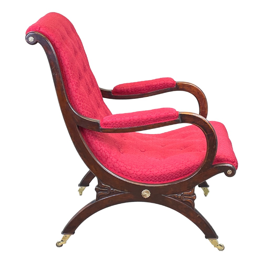 A Regency mahogany library armchair featuring button-backed red upholstery, curved scroll arms, and brass castors. View VIII