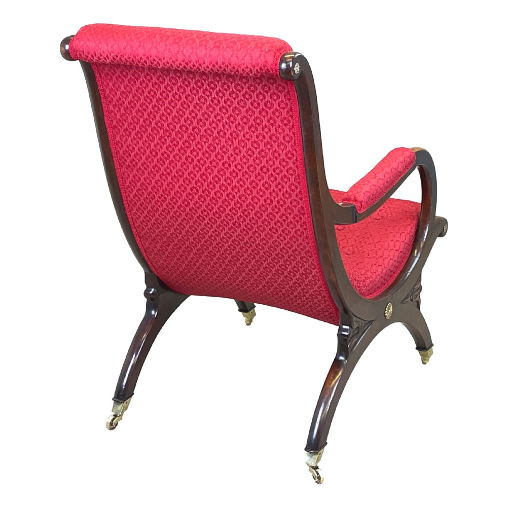 A Regency mahogany library armchair featuring button-backed red upholstery, curved scroll arms, and brass castors. View XI