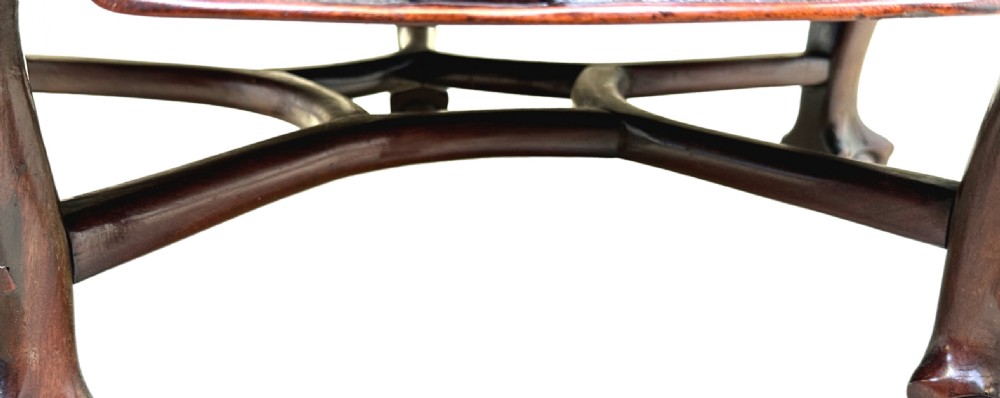 A low circular dark hardwood coffee table featuring hand-carved foliage and animal relief designs along the apron and supported by cabriole legs. View IV