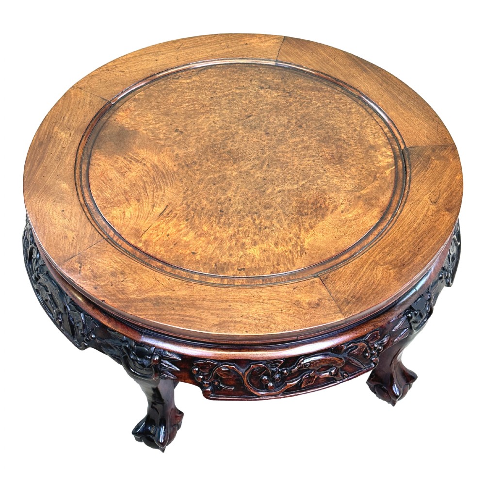 A low circular dark hardwood coffee table featuring hand-carved foliage and animal relief designs along the apron and supported by cabriole legs. View VI