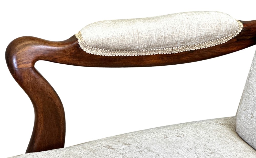 A pair of 19th-century rosewood library armchairs featuring textured beige button-backed upholstery, padded armrests, curved timber supports, turned front legs, and brass castors. View V