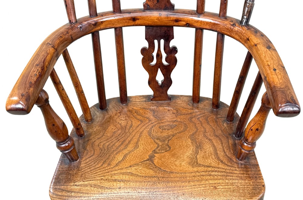 An antique child-sized Windsor armchair made of warm brown wood with turned legs, a hoop back, and a central pierced splat. View X