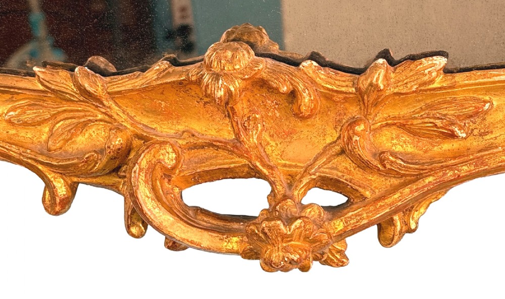 An ornate giltwood wall mirror in the Rococo style featuring asymmetrical scrollwork, acanthus leaves, and a pierced carved crest. View VII