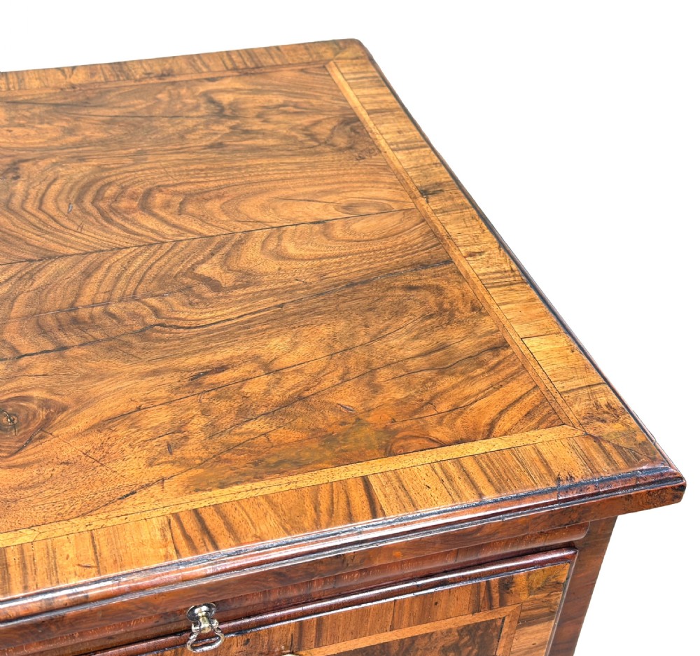 An 18th-century Georgian walnut chest of drawers featuring four graduated drawers with crossbanded borders, brass swing handles, a brushing slide, and bracket feet. View VI