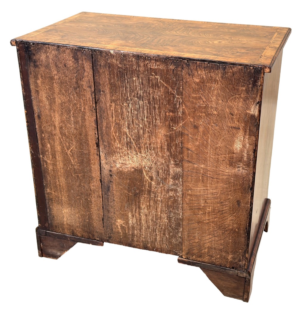 An 18th-century Georgian walnut chest of drawers featuring four graduated drawers with crossbanded borders, brass swing handles, a brushing slide, and bracket feet. View X