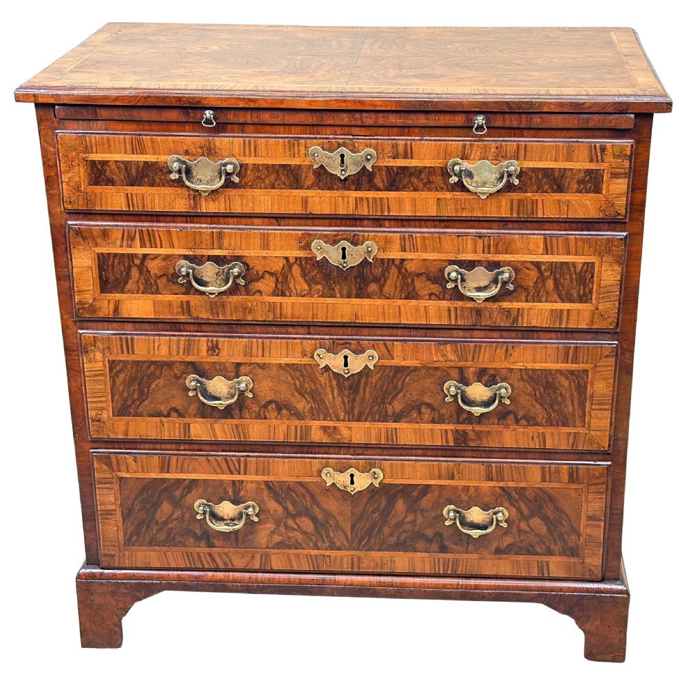 An 18th-century Georgian walnut chest of drawers featuring four graduated drawers with crossbanded borders, brass swing handles, a brushing slide, and bracket feet. View XI