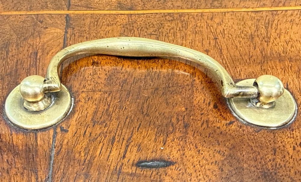 An 18th-century rectangular Georgian walnut tea caddy featuring herringbone stringing, a brass carrying handle on the lid, and a shaped brass escutcheon on the front face. View IX