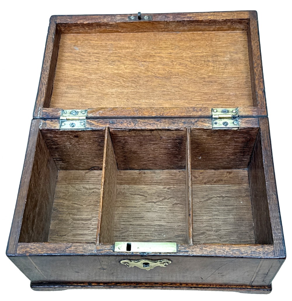 An 18th-century rectangular Georgian walnut tea caddy featuring herringbone stringing, a brass carrying handle on the lid, and a shaped brass escutcheon on the front face. View X