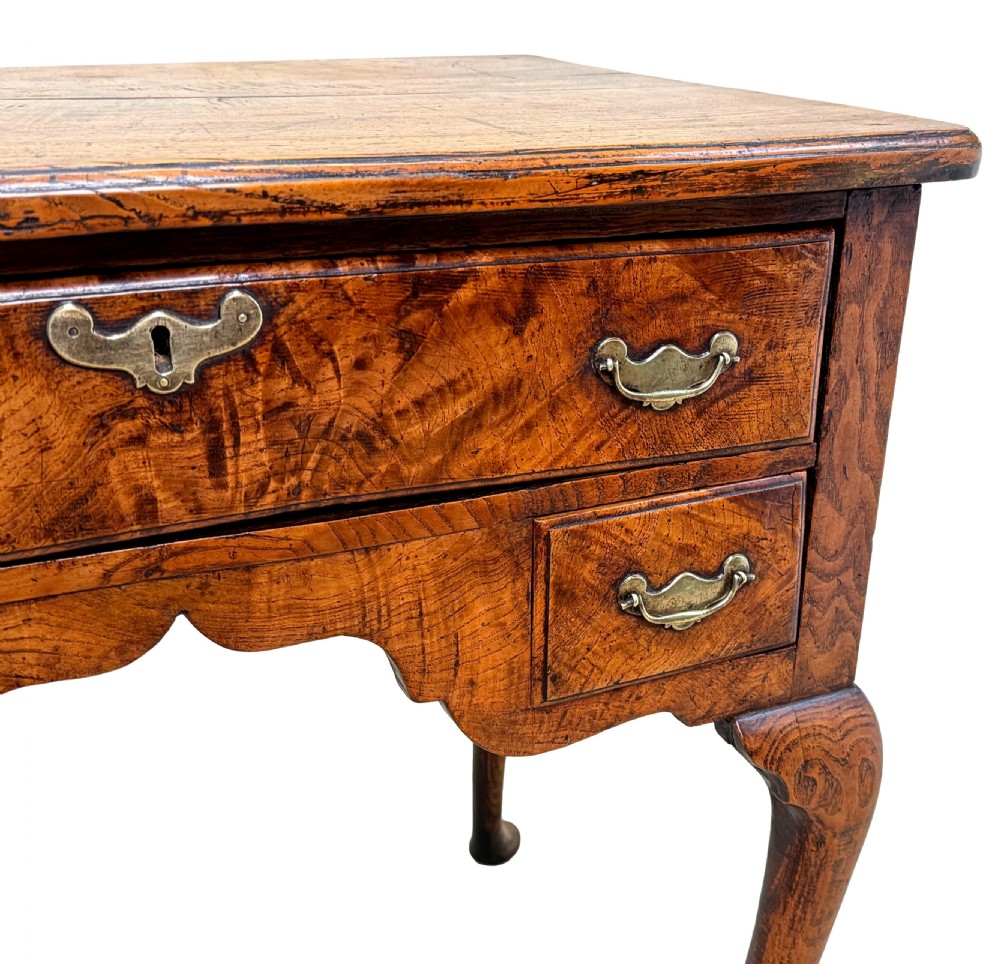 An 18th-century Georgian quilted elm lowboy featuring three drawers with brass handles, a shaped kneehole apron, and four slender cabriole legs. View IV