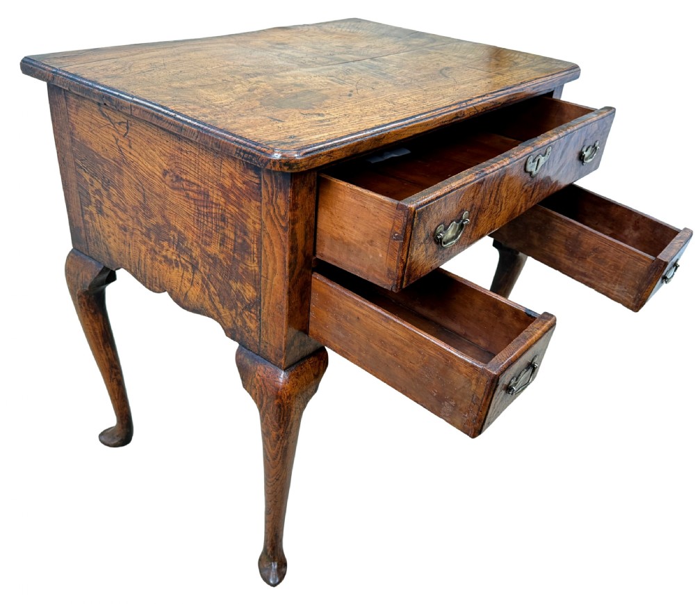 An 18th-century Georgian quilted elm lowboy featuring three drawers with brass handles, a shaped kneehole apron, and four slender cabriole legs. View VI