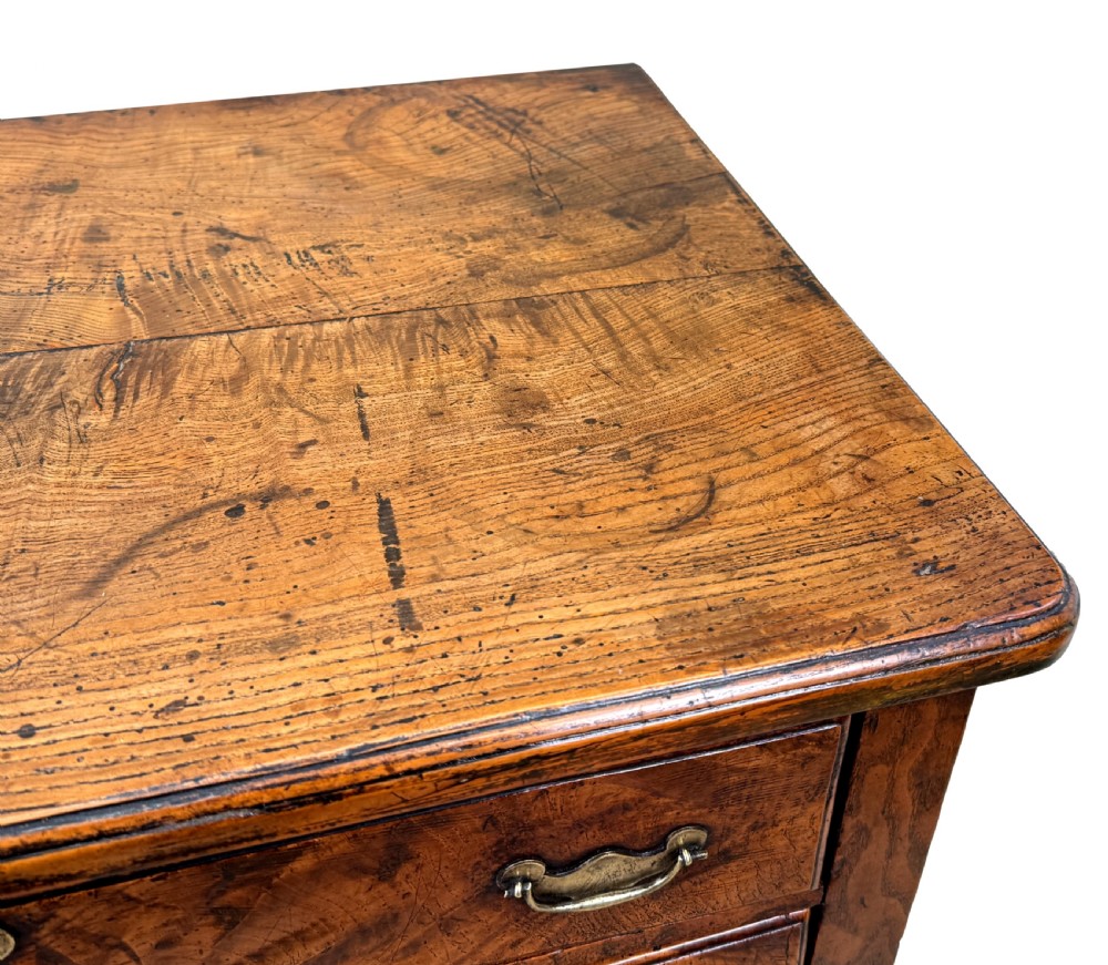 An 18th-century Georgian quilted elm lowboy featuring three drawers with brass handles, a shaped kneehole apron, and four slender cabriole legs. View VII