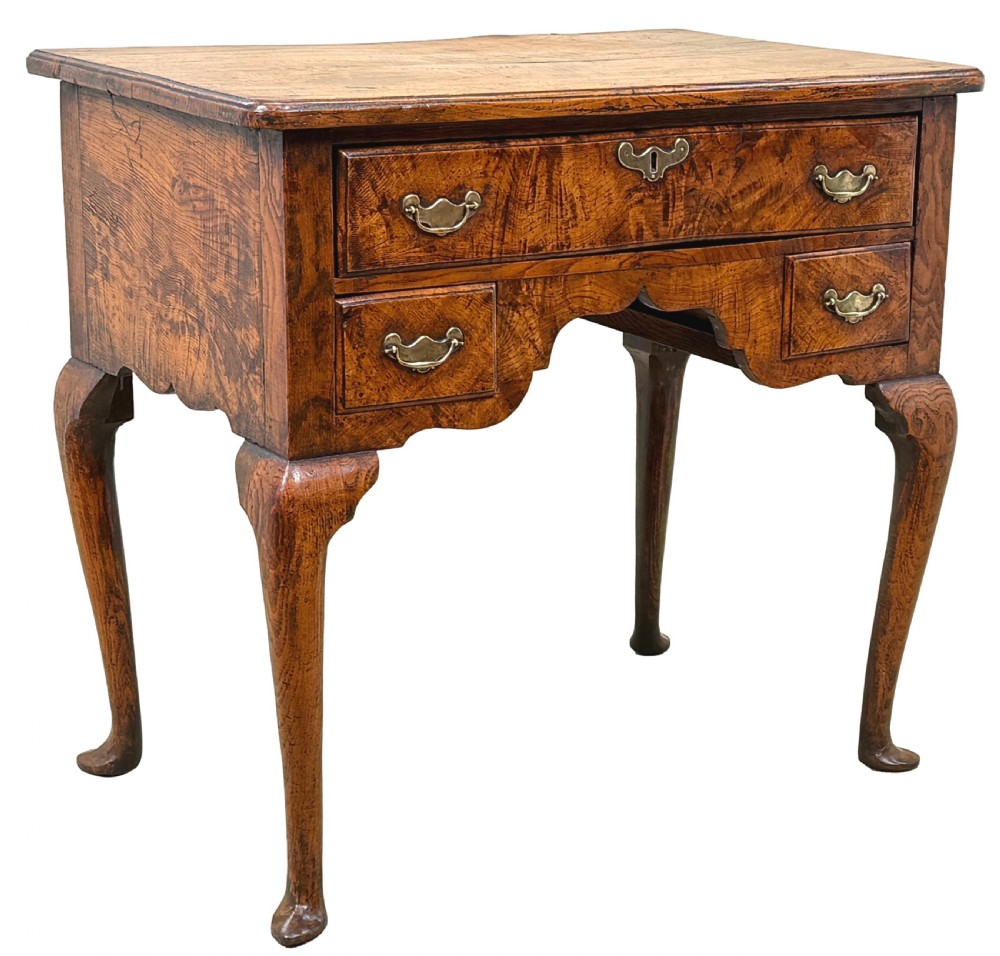 An 18th-century Georgian quilted elm lowboy featuring three drawers with brass handles, a shaped kneehole apron, and four slender cabriole legs. View X