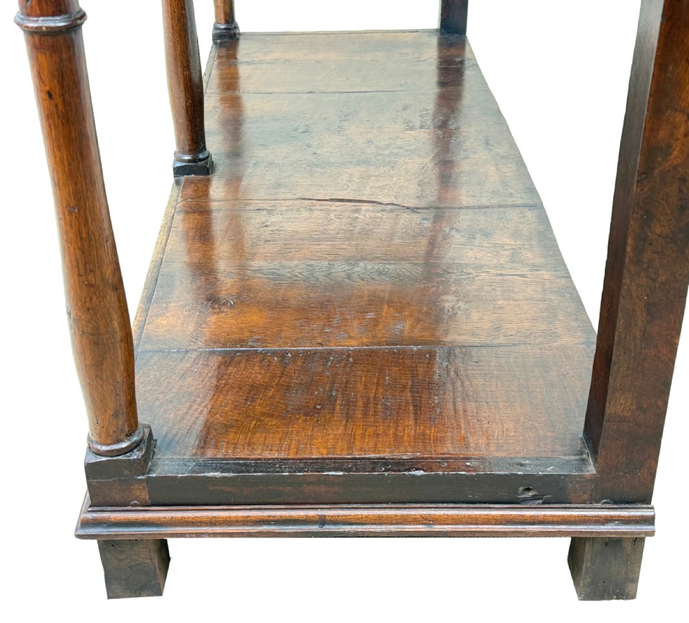 A late 18th-century Georgian oak dresser base featuring two drawers with brass swan-neck handles, turned front legs, and a lower pot board shelf. View V