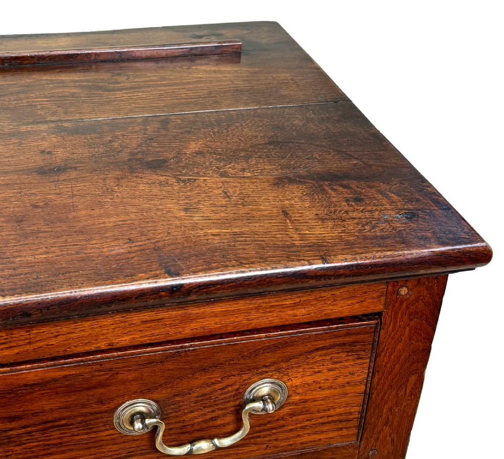 A late 18th-century Georgian oak dresser base featuring two drawers with brass swan-neck handles, turned front legs, and a lower pot board shelf. View VII