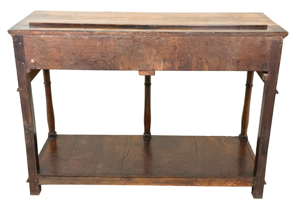 A late 18th-century Georgian oak dresser base featuring two drawers with brass swan-neck handles, turned front legs, and a lower pot board shelf. View XII