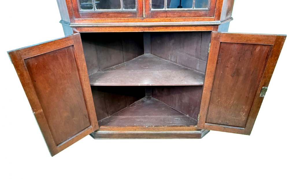 A tall two-part Georgian mahogany corner cabinet featuring upper astragal glazed doors and panelled lower doors. View VIII