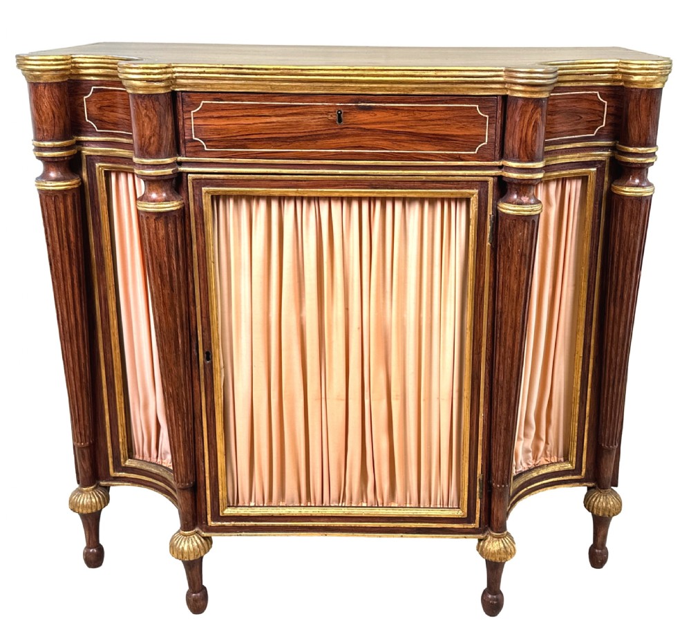 An antique Regency style breakfront side cabinet featuring simulated rosewood finishing, gold leaf gilded columns, and doors set with pleated pink fabric. View XIII