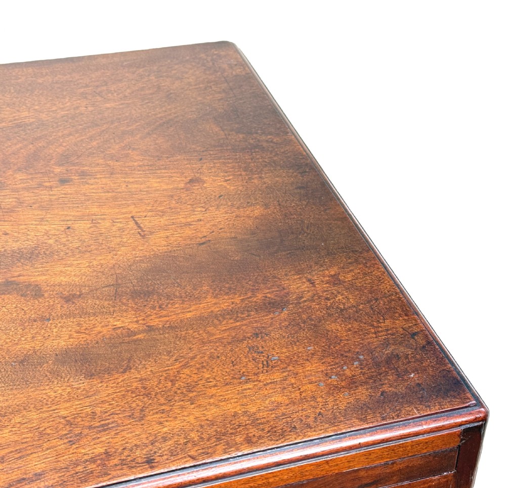 An 18th-century Georgian mahogany chest of drawers featuring four graduated drawers, brass swan-neck handles, a pull-out brushing slide, and sturdy bracket feet. View VIII