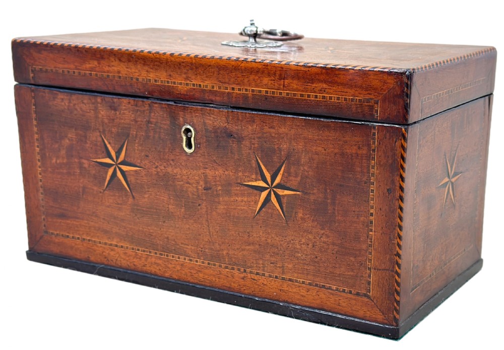 A rectangular 18th-century mahogany tea caddy featuring inlaid wooden star motifs on the front panel and a brass ring handle on top.
