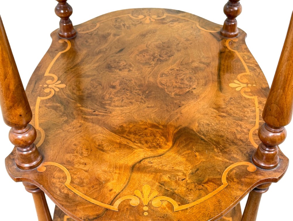 A 19th-century three-tiered burr walnut etagere featuring floral marquetry inlays, slender turned supports, and brass castors. View IV