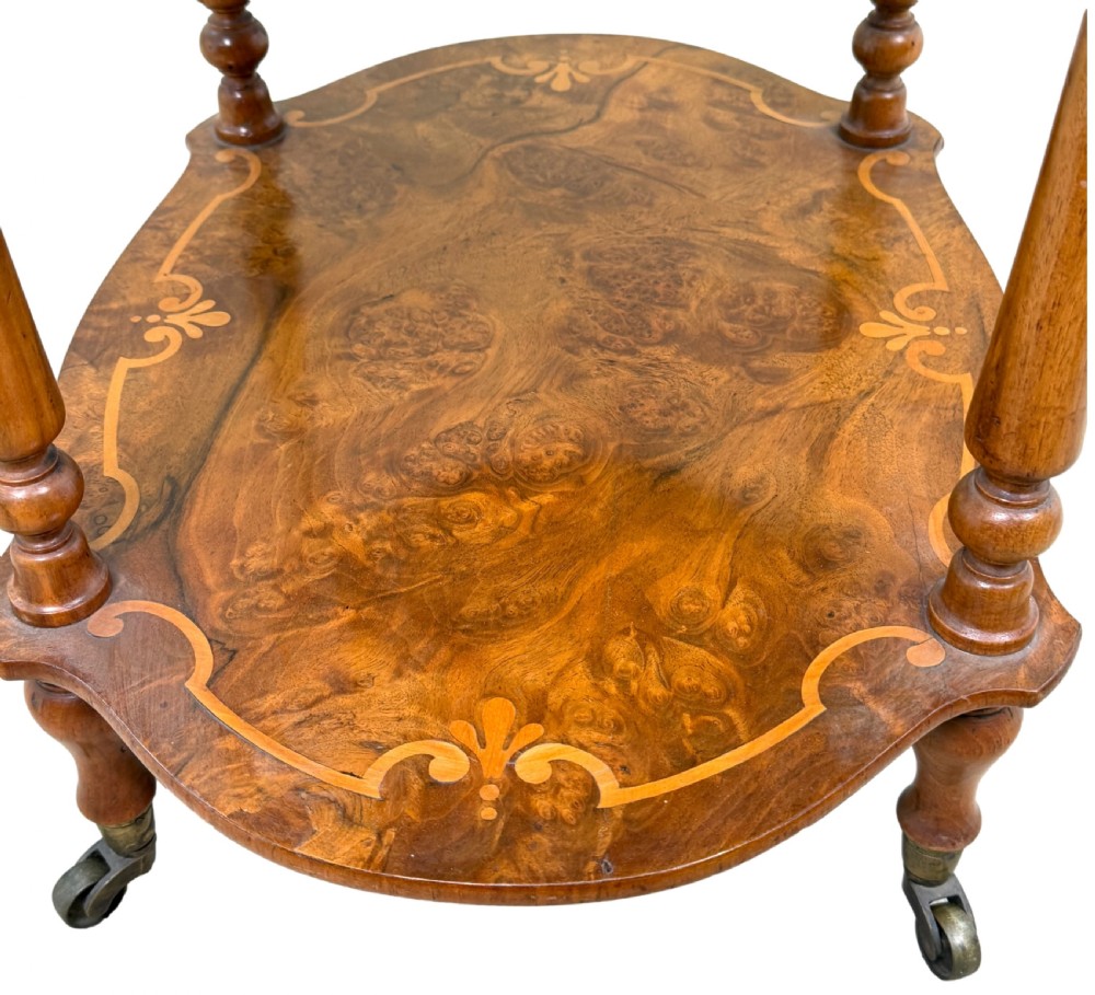 A 19th-century three-tiered burr walnut etagere featuring floral marquetry inlays, slender turned supports, and brass castors. View V