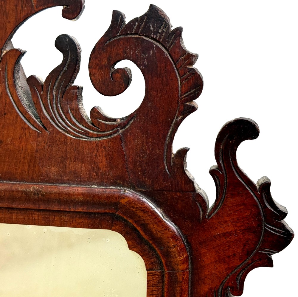 An 18th-century Georgian wall mirror made of dark walnut wood featuring an ornate fretwork crest and scrolled apron around a rectangular mirror plate. View IV