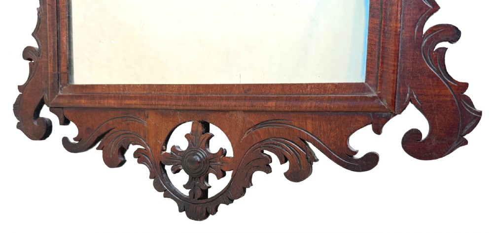 An 18th-century Georgian wall mirror made of dark walnut wood featuring an ornate fretwork crest and scrolled apron around a rectangular mirror plate. View VII
