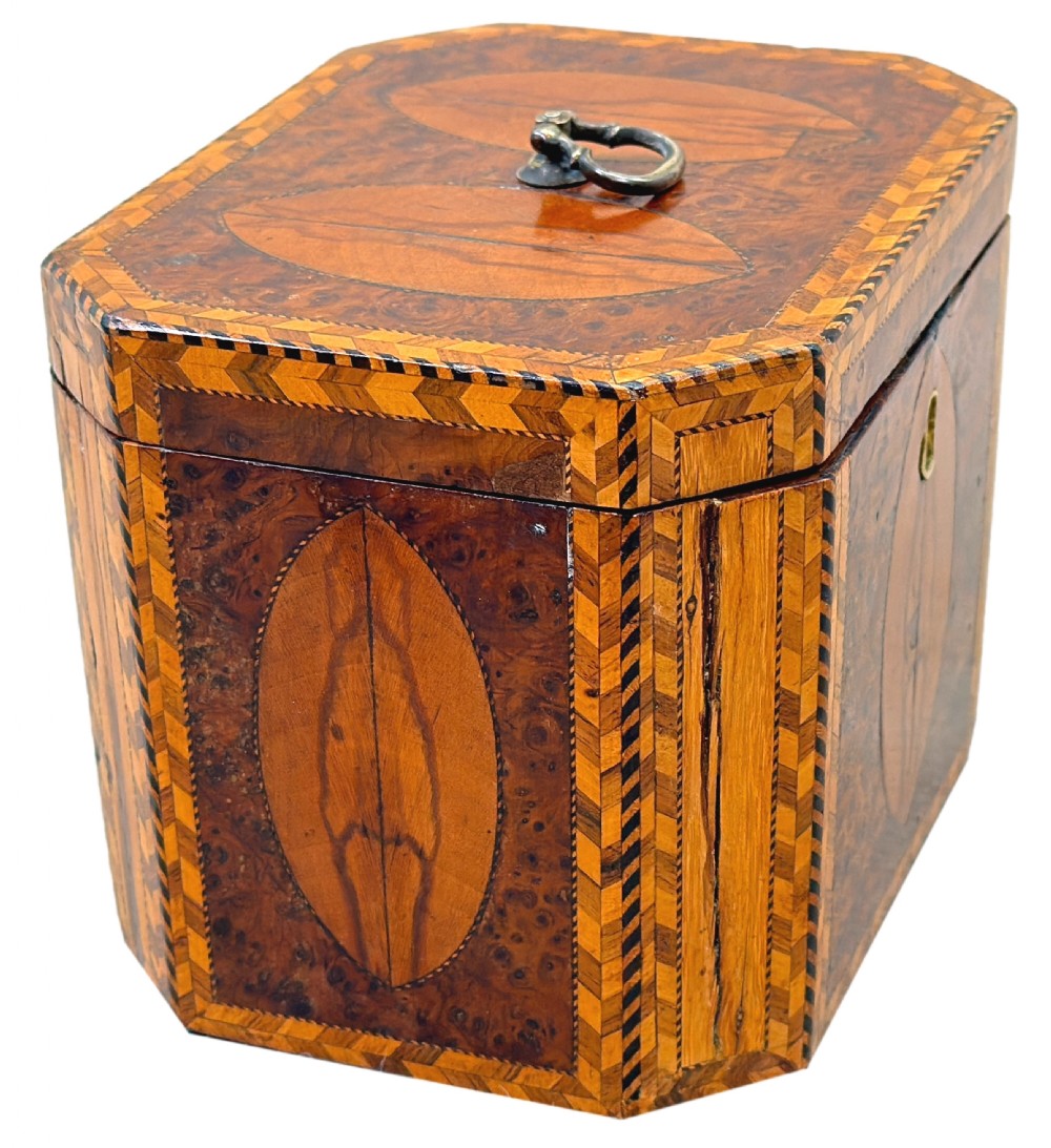 An 18th-century octagonal Georgian tea caddy crafted from burr yew wood with chevron stringing, oval marquetry panels, a brass top handle, and a brass keyhole escutcheon. View II