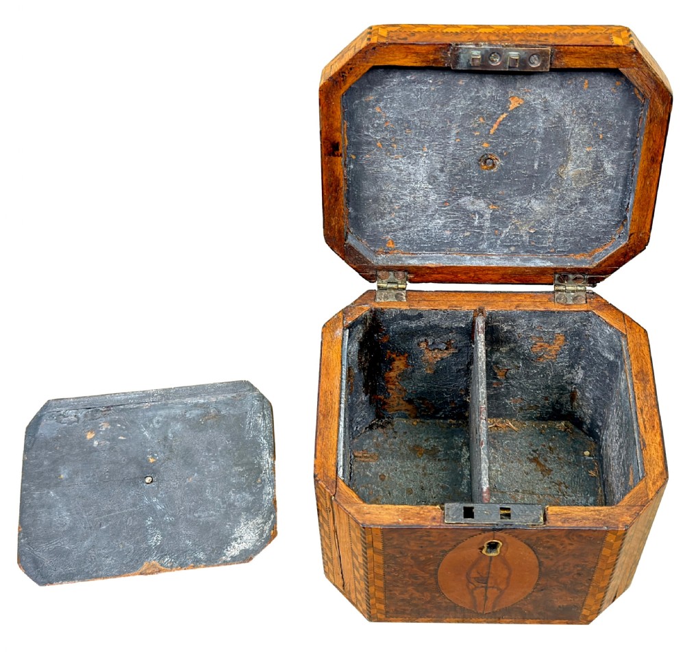 An 18th-century octagonal Georgian tea caddy crafted from burr yew wood with chevron stringing, oval marquetry panels, a brass top handle, and a brass keyhole escutcheon. View V